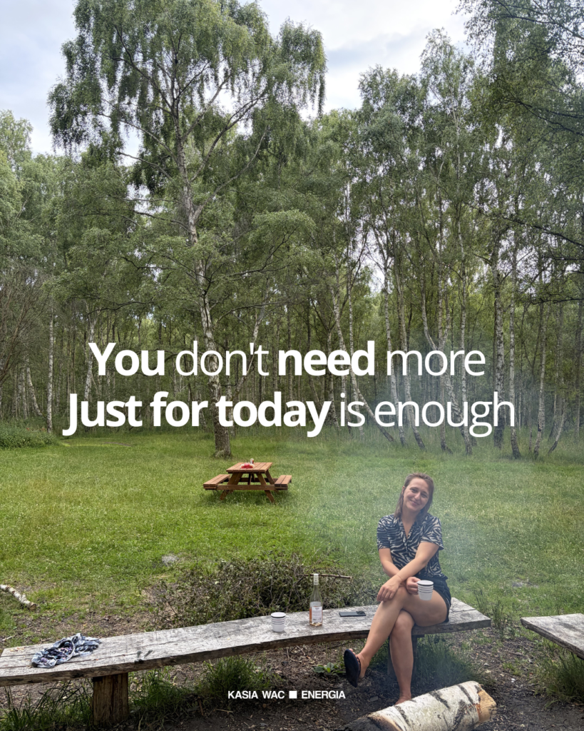Kasia Wac, Reiki Master Teacher leading Reiki courses in Copenhagen, sitting by a lake and fire with the words “You don’t need more. Just for today is enough.”
